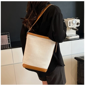 Chic bucket bag featuring canvas and leather stitching detail on a model shoulder