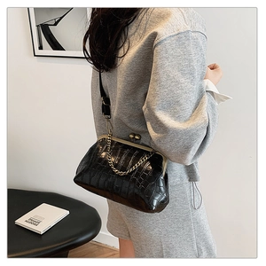 Detail of vintage black crocodile pattern bag with gold chain strap on shoulder