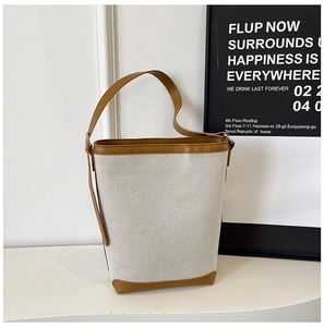 Detail of canvas bucket bag featuring brown leather trim and reinforced bottom corners