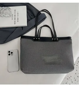 Close-up of contrast large tote bag in grey canvas and black leather with phone for scale