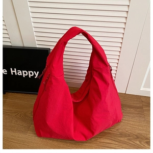 Detail of red large capacity nylon hobo bag featuring side zipper pockets and wide strap