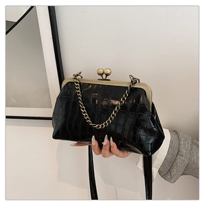 Detail of vintage black crocodile pattern shell bag with bronze clasp and metal chain