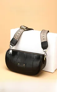 Close-up of black quilted leather crossbody bag with ethnic pattern wide shoulder strap