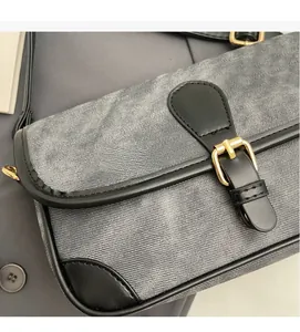 Close-up of grey denim texture, black leather trim and golden metal buckle on the bag
