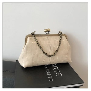 Close-up of cream crocodile pattern shell bag with vintage metal frame and chunky chain
