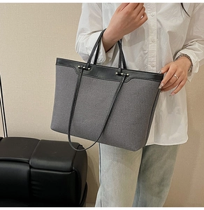 Detail of grey denim tote bag with black leather trim and white contrast stitching details