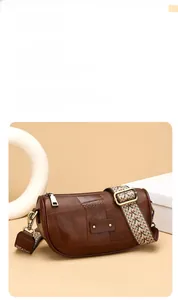 Detail of vintage brown shoulder bag showing retro herringbone wide woven strap and metal hardware