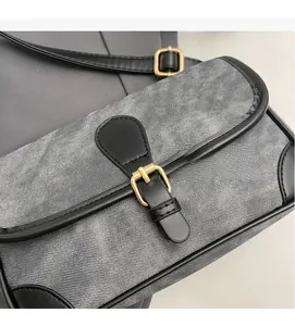 Detail of gray denim handbag with black leather trim and golden metal buckle