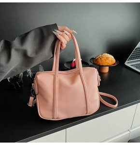 Detailed close-up of pink litchi grain texture handbag with adjustable strap for women