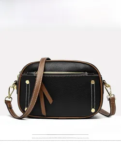 Front detail of black pebble leather shoulder bag with brown piping and gold studs