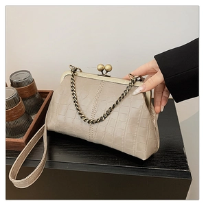 Detail of beige crocodile pattern shell bag with vintage metal frame and bead clasp