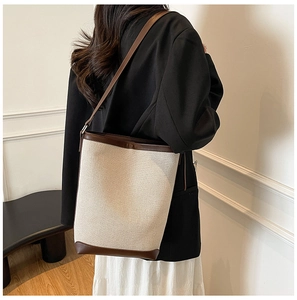 Classic beige canvas and brown leather patchwork bucket bag shown on model for daily styling