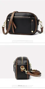 Detail of black lychee grain leather crossbody bag with brown trim and gold hardware