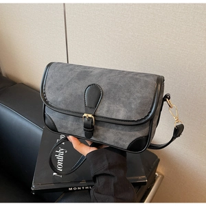 Close-up of grey denim texture flap bag with black leather trim and gold buckle detail
