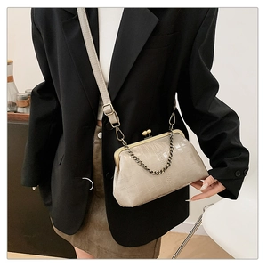 Detail of grey crocodile pattern handbag with metal ball clasp and bronze chain