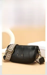 Detail of black leather crossbody bag with golden studs and wide geometric fabric strap