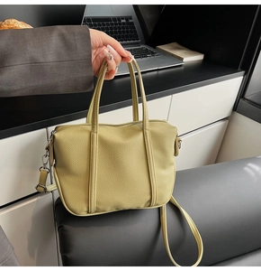 Detail of avocado green litchi texture handbag with top handles and adjustable strap
