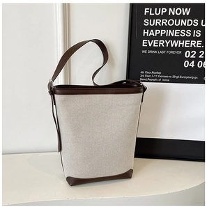 Detail of color-block canvas bucket bag with brown leather trim and corner protection