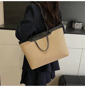 Large beige canvas tote bag with black leather straps shown on shoulder for daily commute