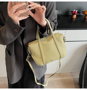 Detail of light green litchi texture leather handbag with adjustable crossbody strap