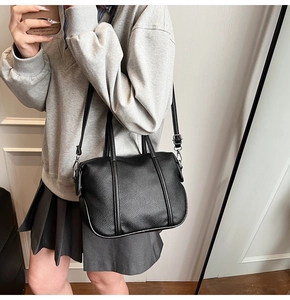 Detailed shot of black lychee grain leather tote bag with silver zipper and shoulder strap