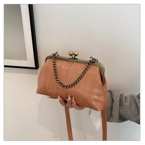 Detail of retro shell bag with crocodile texture and bronze kiss-lock clasp