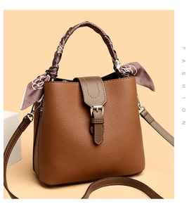 Macro detail of brown lychee grain leather bucket bag with silk scarf on handle