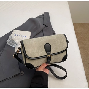 Close-up of grey-green denim square bag with black leather trim and gold buckle
