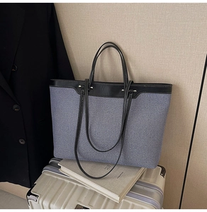 Detail of canvas tote bag with leather trim and contrast stitching on a suitcase
