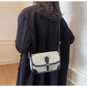 Detail of grey canvas crossbody bag with black leather trim and gold metal clasp