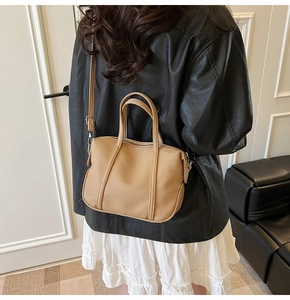 Back view of a model wearing a camel lychee pattern leather bucket bag on shoulder