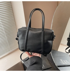 Detail of black lychee grain leather handbag with silver metal hardware and detachable strap