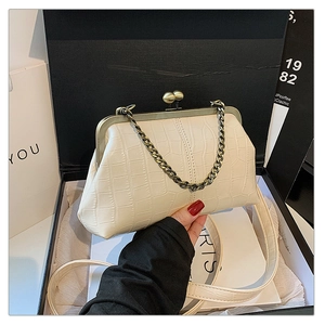 Detail of cream crocodile embossed shell bag featuring vintage metal clasp and strap