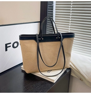 Close-up of contrast stitching on beige canvas and black leather tote bag details