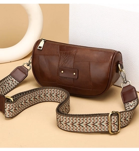 Detail of vintage brown cylinder crossbody bag with wide woven strap and bronze hardware