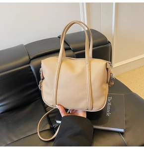 Detailed view of beige lychee pattern leather tote bag with silver zipper and slim handles