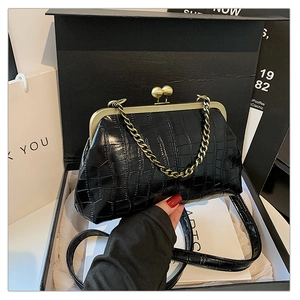Detail of glossy black crocodile embossed shell bag with vintage gold clasp and chain