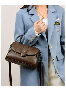 Détail d'un sac à main en cuir marron texturé avec boucle ronde porté à l'épaule