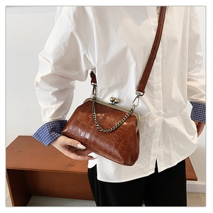 Detail of vintage brown crocodile texture crossbody bag with metal clasp on model