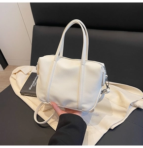 Close-up of white lychee grain texture and silver hardware on a leather handbag