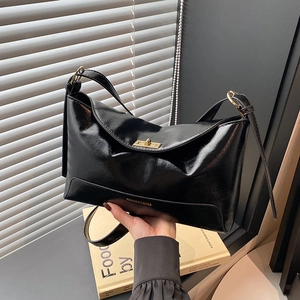 Large black glossy leather tote bag with gold clasp and shoulder straps for women