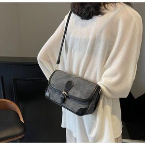 Dark grey matte shoulder bag with black trim worn by a model in a minimal setting