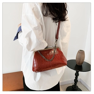 Detail of a retro burgundy crocodile pattern shell bag with a bead chain on a female model