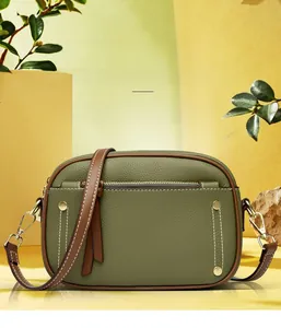 Detail of olive green pebbled leather bag with contrast brown piping and gold rivets
