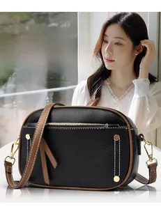 Detail of contrast stitch black lychee leather bag with brown strap and gold hardware