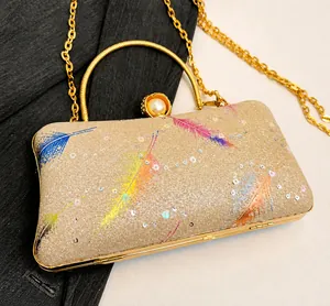 Detalle de bolso de noche con lentejuelas doradas, plumas de colores y broche de perla