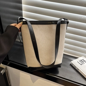 Minimalist canvas and black leather bucket bag shown in natural window light