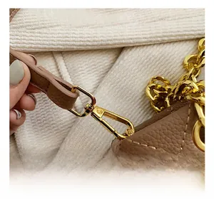 Détail du fermoir mousqueton doré sur un sac en cuir marron matelassé avec chaîne