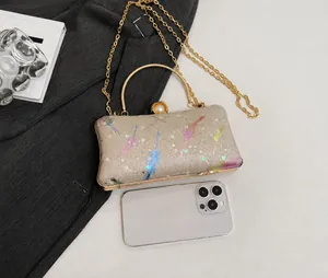 Détail de la pochette de soirée champagne avec paillettes plumes, anse dorée et perles