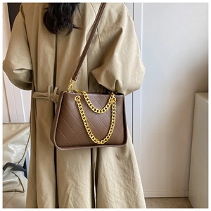 Détail du sac matelassé marron foncé avec bandoulière en chaîne dorée à l'épaule